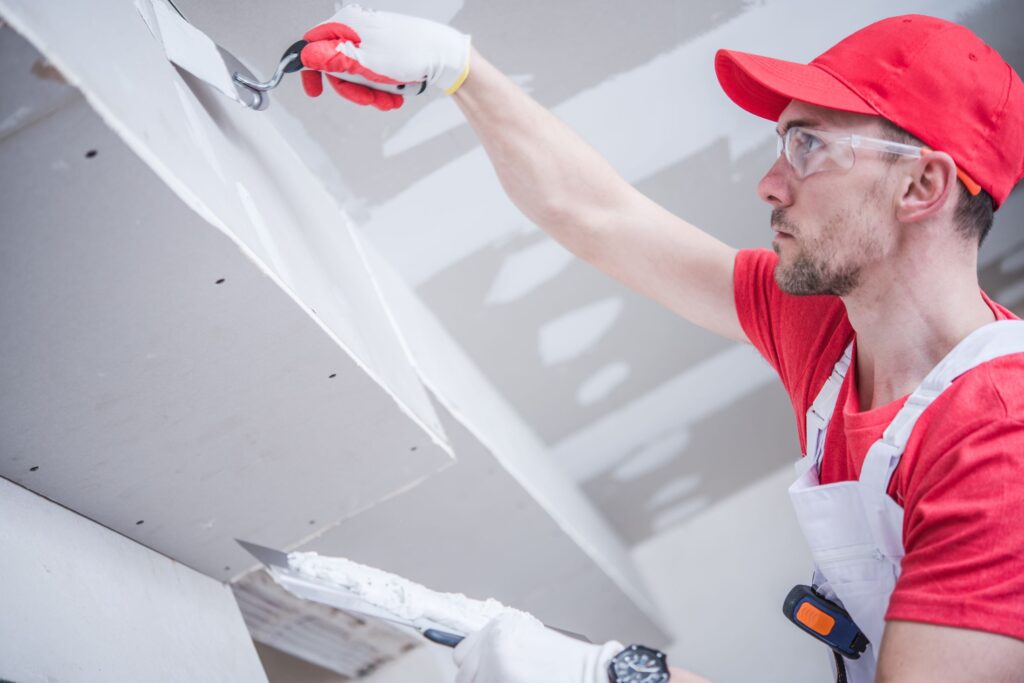 worker finishing drywall in a basement