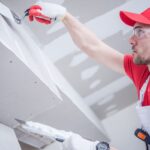 worker finishing drywall in a basement