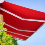 Awning Canopy. Retractable Awning Manual Pergola Roof Patio. Canvas Pergola Awning. Modern Red Retractable Patio Awning Sunshade on Sky Background.