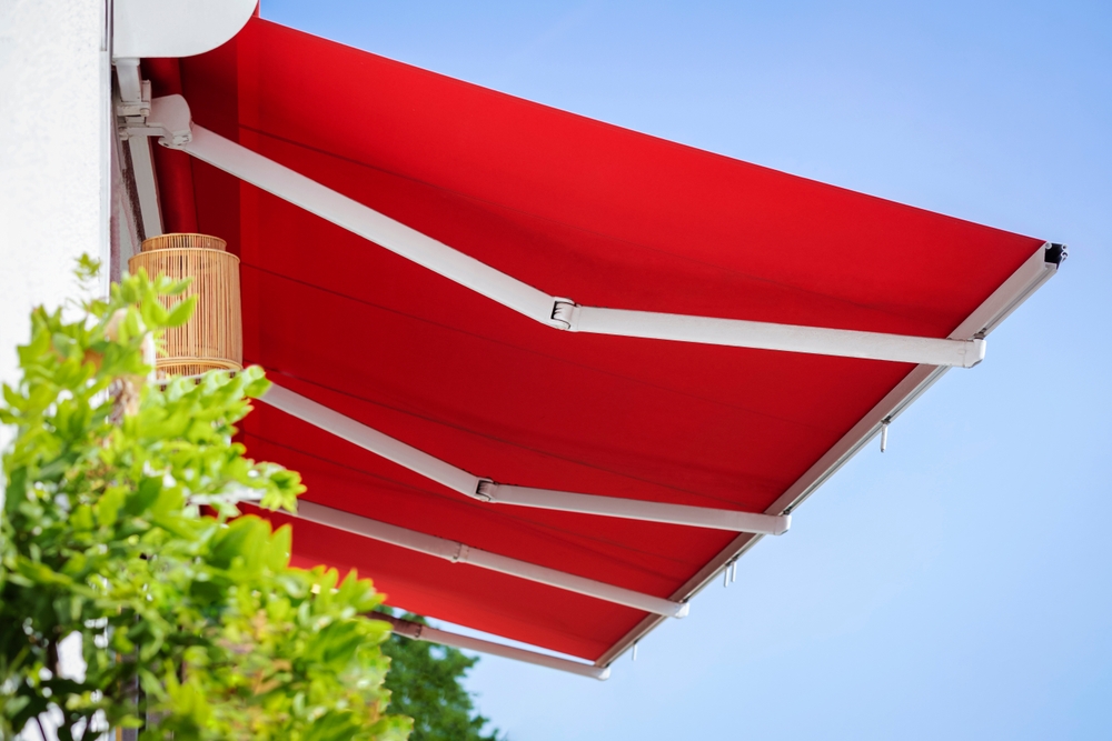 Awning Canopy. Retractable Awning Manual Pergola Roof Patio. Canvas Pergola Awning. Modern Red Retractable Patio Awning Sunshade on Sky Background.