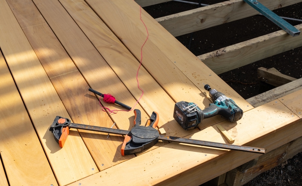 Old builders tools and red string on new wooden decking under construction at end of day.